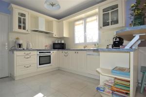 a kitchen with white cabinets and a sink at Maison confortable séjour spacieux, belle terrasse avec grand jardin avec jeux extérieurs près Bayeux et Omaha Beach in Saonnet