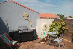 a patio with a grill and a table and chairs at FRANDIERE in Barbâtre