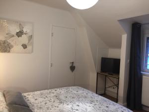 a small bedroom with a bed and a television at L'ESCALE FONTAINE SIMON in Fontaine-Simon