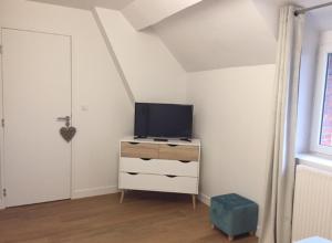 ein Wohnzimmer mit einem TV und einer Kommode mit einem tvicterictericter in der Unterkunft L'ESCALE FONTAINE SIMON in Fontaine-Simon