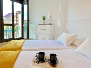 a white bed with two cups and a tray on it at Apartamento El Socaire Playa Trengandín in Noja