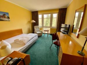 a hotel room with a bed and a television at Park Hotel Fasanerie Neustrelitz in Neustrelitz