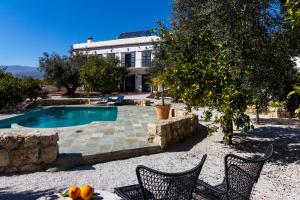 uma casa com piscina com duas cadeiras e uma laranjeira em Jardin de los limones em Melegis