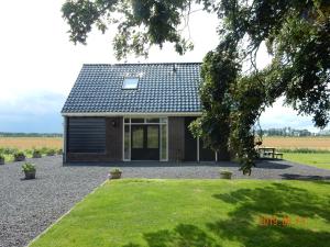 a small house with a roof on a gravel driveway at UNESCO de Beemster, vakantiewoning in Noordbeemster