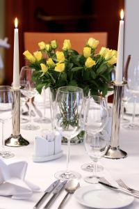 a table with glasses and a vase of yellow roses at Hotel zur Altstadt in Freudenberg