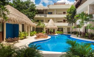 a resort with a swimming pool with chairs and a building at Amazing Poolside Bliss, Private Terrace with Hot Tub in Aldea Zama in Tulum