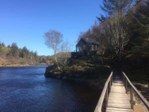 una pasarela de madera que conduce a una cabaña en un río en Bonnie Haven, en Lochinver