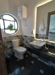 uma casa de banho com um WC, um lavatório e um espelho. em Madina Hostel no Cairo