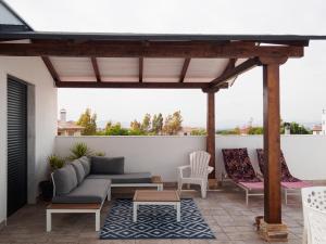 un patio con sofá y sillas en el techo en Atico Aligma, en Granada