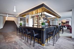 - un bar dans une pièce avec des chaises noires dans l'établissement Mondorf Parc Hotel & Spa, à Mondorf-les-Bains