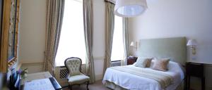 um quarto com uma cama, uma cadeira e janelas em Durrants Hotel em Londres