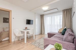 ein Wohnzimmer mit einem Sofa und einem Tisch in der Unterkunft Apartament Malūno in Palanga