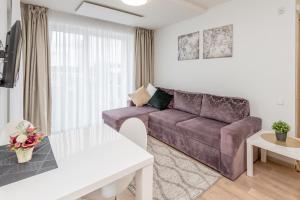 een woonkamer met een bank en een tafel bij Apartament Malūno in Palanga