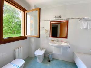 a bathroom with a sink and a toilet and a mirror at Hotel EntreRobles in Baiona