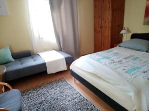 ein Schlafzimmer mit einem Bett, einem Sofa und einem Fenster in der Unterkunft Kőszeghegyalja Vendégház in Horvátzsidány