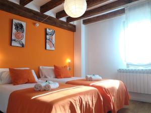 two beds in a room with orange walls at Casa Rural Madera y Sal in Salinas de Añana