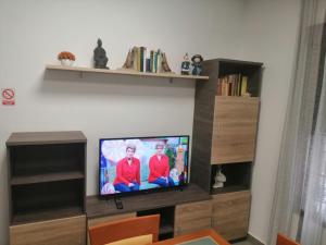 telewizor z płaskim ekranem siedzący na drewnianym centrum rozrywki w obiekcie El LEGADO w mieście Andújar