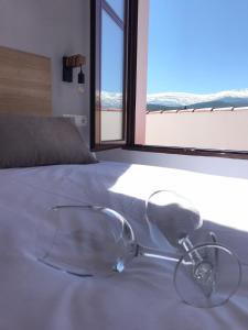 Un par de gafas sentadas en una cama con ventana en Hotel El Picón de Sierra Nevada en Jerez del Marquesado