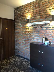 a room with a brick wall and a black dresser at Pokoje Gościnne Atelier in Orneta