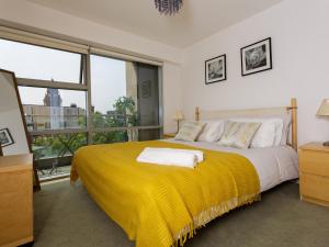 a bedroom with a large bed with a yellow blanket at Live in Leeds Millenium Square Apartment in Leeds