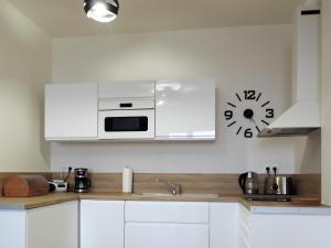 una cocina con armarios blancos y un reloj en la pared en Apartman Bery, Vysoké Tatry, en Starý Smokovec