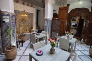 ein Restaurant mit Tischen und Stühlen mit Blumen darauf in der Unterkunft Riad Adarissa in Fès