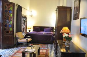 a bedroom with a bed and a living room at Riad Adarissa in Fez