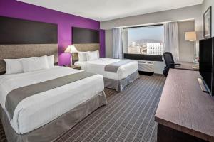 ein Hotelzimmer mit 2 Betten und einer lila Wand in der Unterkunft CHN Hotel Monterrey Centro, Trademark Collection by Wyndham in Monterrey
