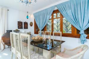 a dining room with a glass table and blue drapes at Villa Anna in Kallirákhi