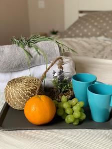 a tray with oranges and grapes and blue cups on a table at Apartman Maroon - Savršen pogled i miran odmor in Lovran