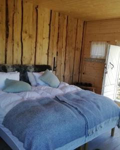a bed in a room with a wooden wall at Eremitstuga Detox resort in Köpmannebro +11 photos