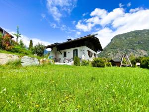 ein Haus auf einem Hügel mit einem grünen Feld in der Unterkunft Ferienhaus Ötztal-Lodge in Sautens