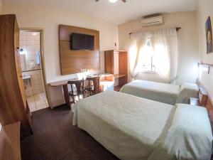ein Hotelzimmer mit zwei Betten und einer kleinen Küche in der Unterkunft Milão Hotel in Porto Alegre + 39 Fotos