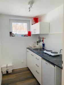 uma cozinha com armários brancos e um balcão preto em Kleine Wohnung im Herzen von Leverkusen Opladen em Leverkusen