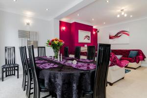a dining room with a table and a red wall at Brooklyn House in Barnet