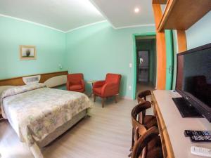 a bedroom with a bed and a flat screen tv at Milão Hotel in Porto Alegre