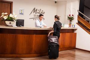 a woman waiting at a cash register with her luggage at Milão Hotel in Porto Alegre