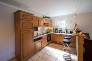 a kitchen with wooden cabinets and a stove top oven at Exklusive Ferienwohnung 'Agger-Blick' mit großer Seeblick-Terrasse & Sauna in Gummersbach