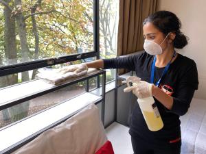 une femme portant un masque facial tenant une bouteille de lait dans l'établissement YMCA Hostel, à Auckland