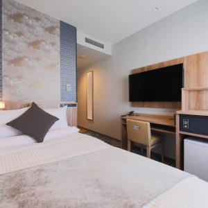 a hotel room with a bed and a desk with a computer at ART HOTEL Aomori in Aomori