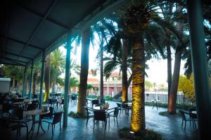 a restaurant with tables and chairs and palm trees at Hotel Victoria in Fortuna