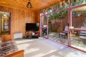a living room with a television and a screened in porch at Piece of Paradise - Kawaha Point Holiday Home in Koutu