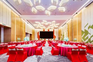 a banquet hall with red tables and chairs and a screen at Holiday Inn Changsha Dawangshan, an IHG Hotel in Changsha