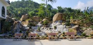dois bancos sentados em frente a uma cascata em A Sim ba be lake hotel em Bak Kan