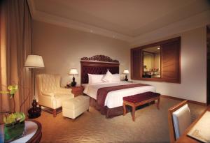 a hotel room with a bed and a chair at Royale Chulan Kuala Lumpur in Kuala Lumpur
