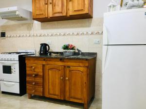 a kitchen with wooden cabinets and a white refrigerator at DLA Apartamentos III in Villa María