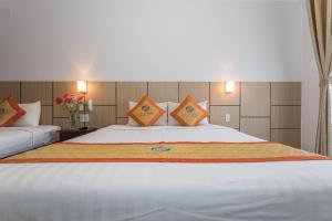 a bedroom with a large white bed with orange pillows at Galaxy Hotel Phu Quoc in Phú Quốc