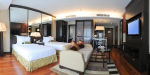 um quarto de hotel com duas camas e um sofá e uma televisão em Micasa All Suites Hotel em Kuala Lumpur