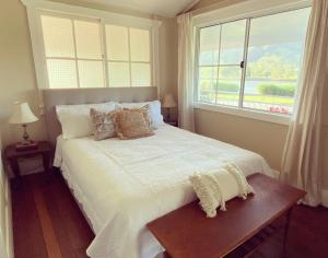 a bedroom with a large white bed with a window at The Belle Riverhouse, Tumbulgum# in Tumbulgum