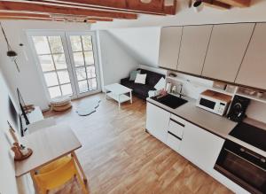 eine Küche und ein Wohnzimmer mit weißen Schränken und einem Tisch in der Unterkunft Apartmán v podkroví in Říčky